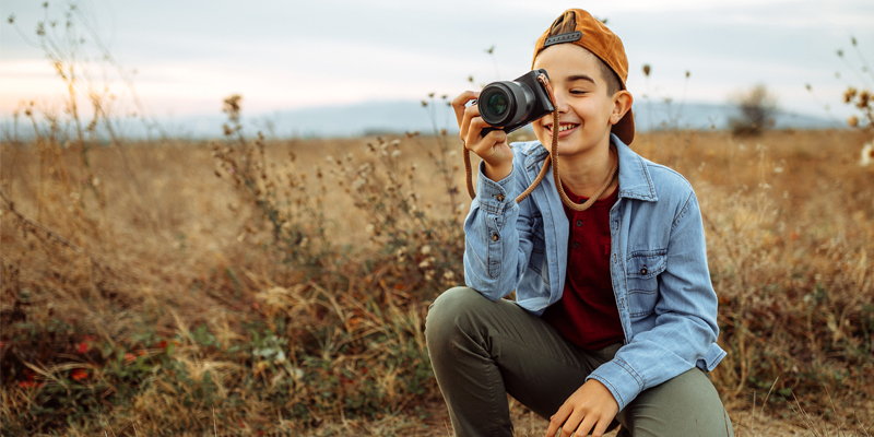 Teenager taking a photograph outside in a field